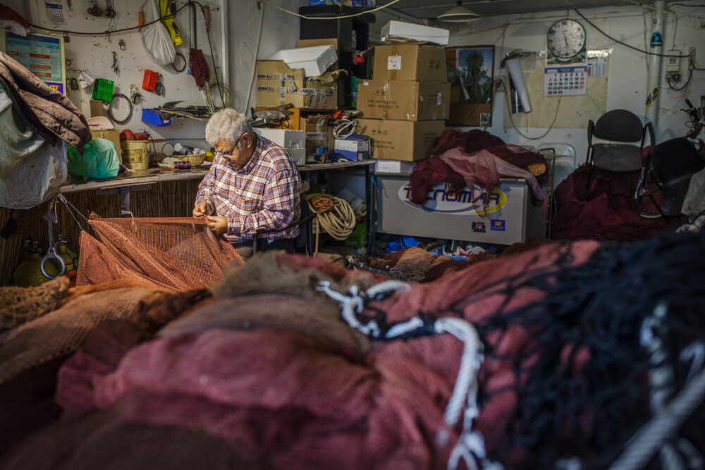 A Fisherman Repairs His Net in a Small Cabin - Tom Bourdon Travel Photography