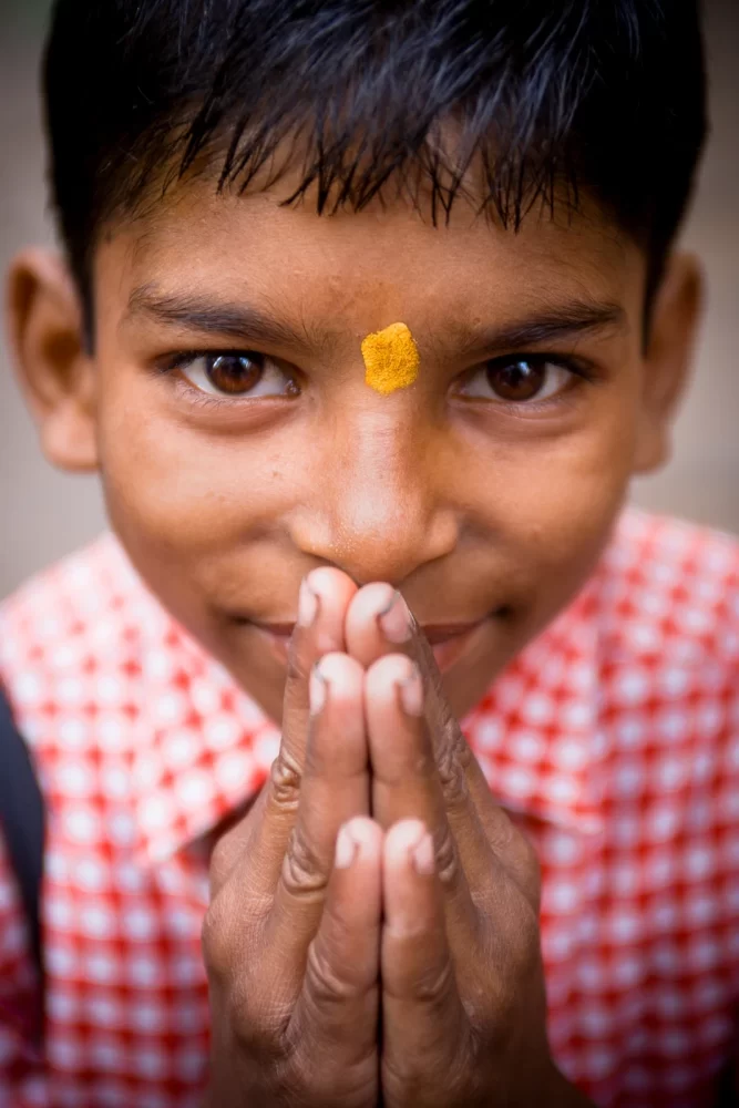 A young Indian boy holds his hands together - Tom Bourdon Travel Photography