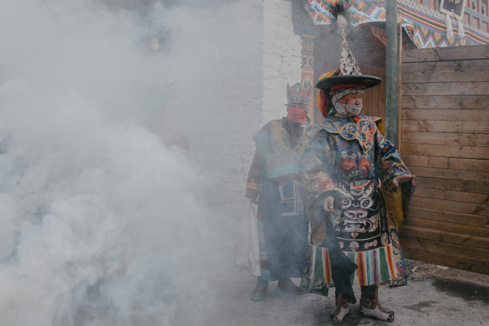 A dancer emerges through smoke, the courtyard briefly reduced to silence and shape.